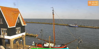 Webcam view of a boat gently floating in the water at Vollenhove Marina, surrounded by calm waves and clear skies.